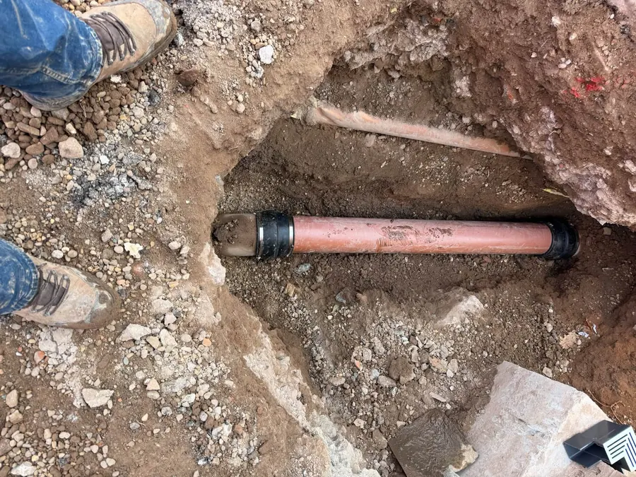 Exposed drain pipe in an excavation for a drain repair, GRW Homes groundworks on a school project
