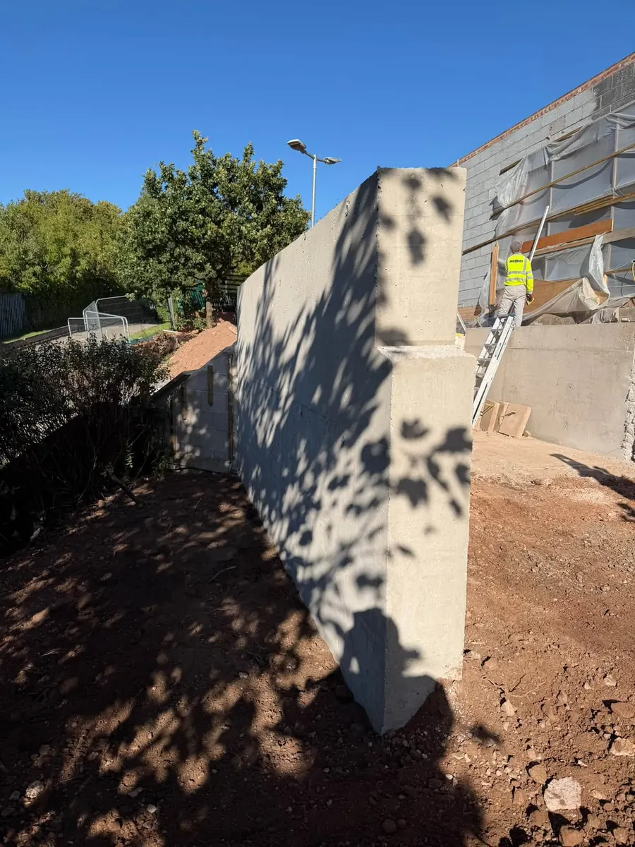 Finished concrete retaining wall beside a building, GRW Homes groundworks on a school project
